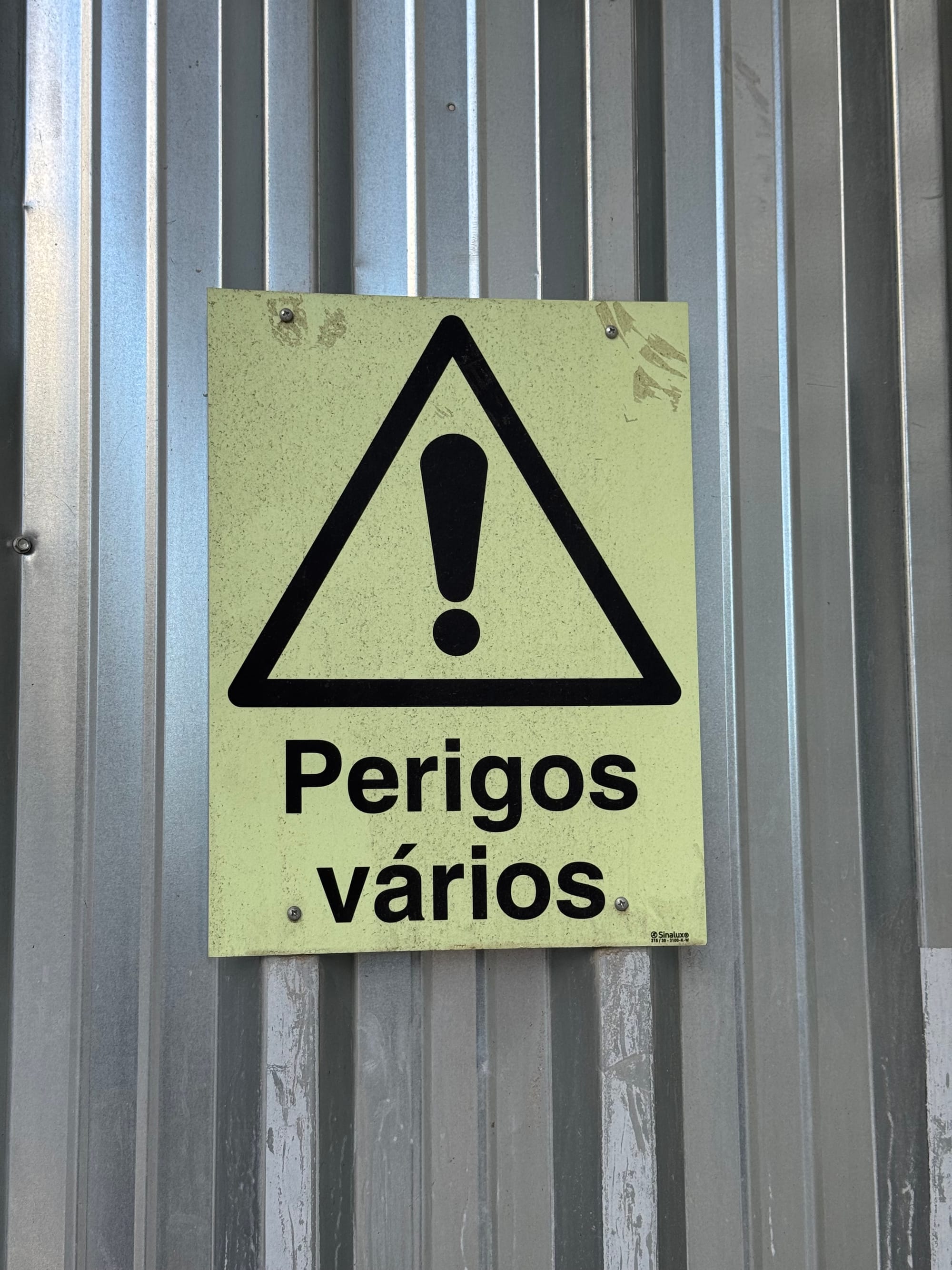 A warning sign saying “perigos vários”.