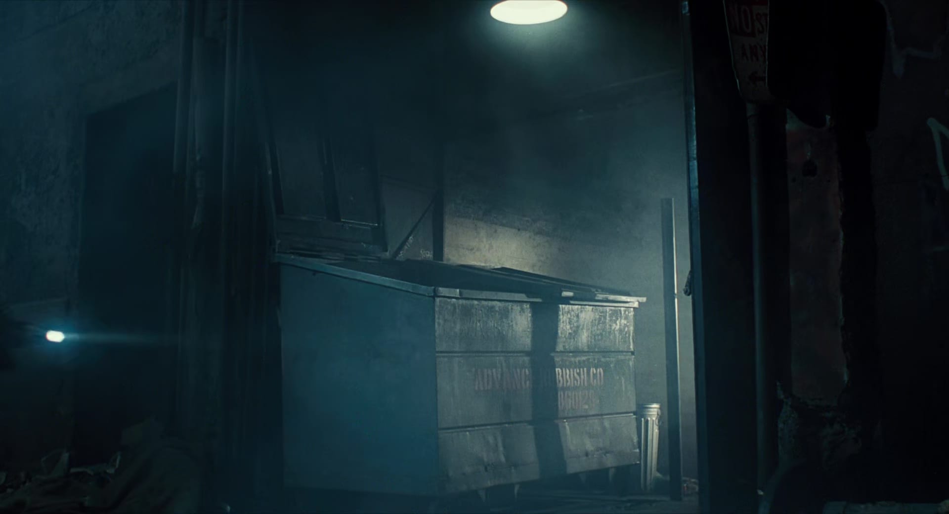 A shot of the famous "Advanced Rubbish Co" dumpster from The Terminator, lit from above with moody, smoky lighting.