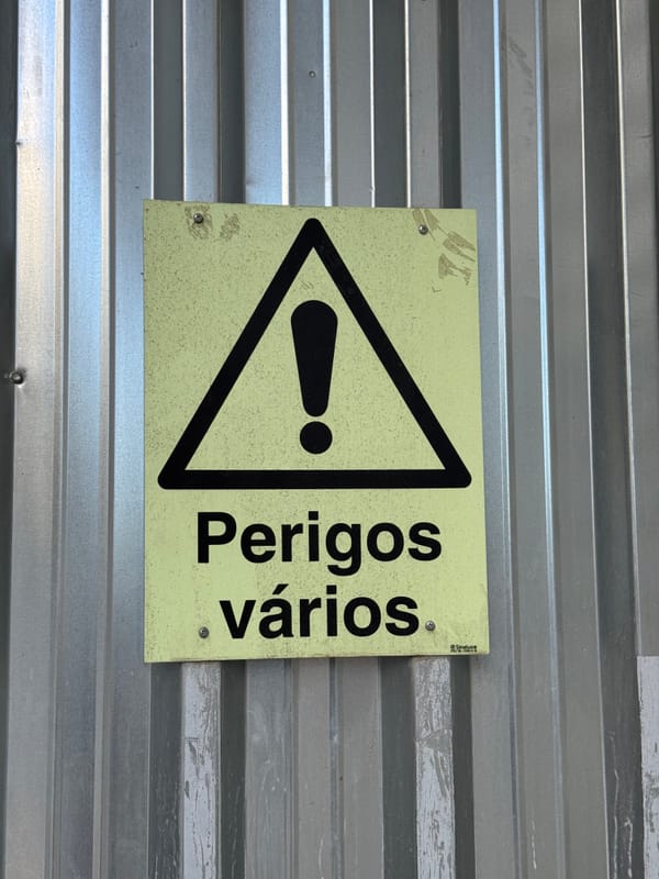 A warning sign saying “perigos vários”.